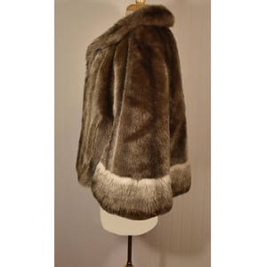 Peut inclure: Une veste en fausse fourrure marron avec une bordure blanche autour des bords. La veste est sur un mannequin blanc.