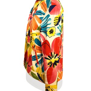 May include: A white jacket with a colorful floral print. The print features large pink, red, yellow, and blue flowers with green leaves.