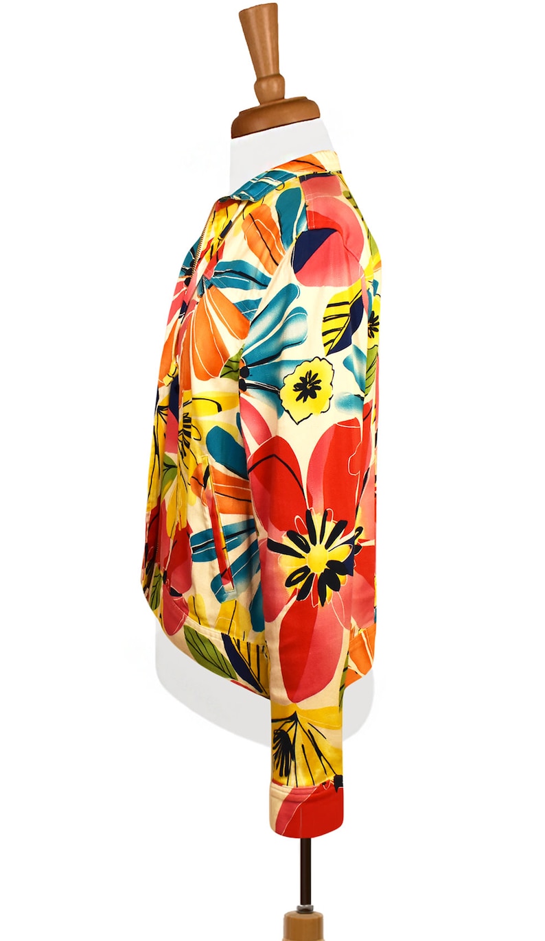 May include: A white jacket with a colorful floral print. The print features large pink, red, yellow, and blue flowers with green leaves.