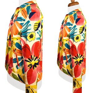 May include: A white jacket with a colorful floral print. The print features large pink, orange, yellow, and blue flowers on a white background.