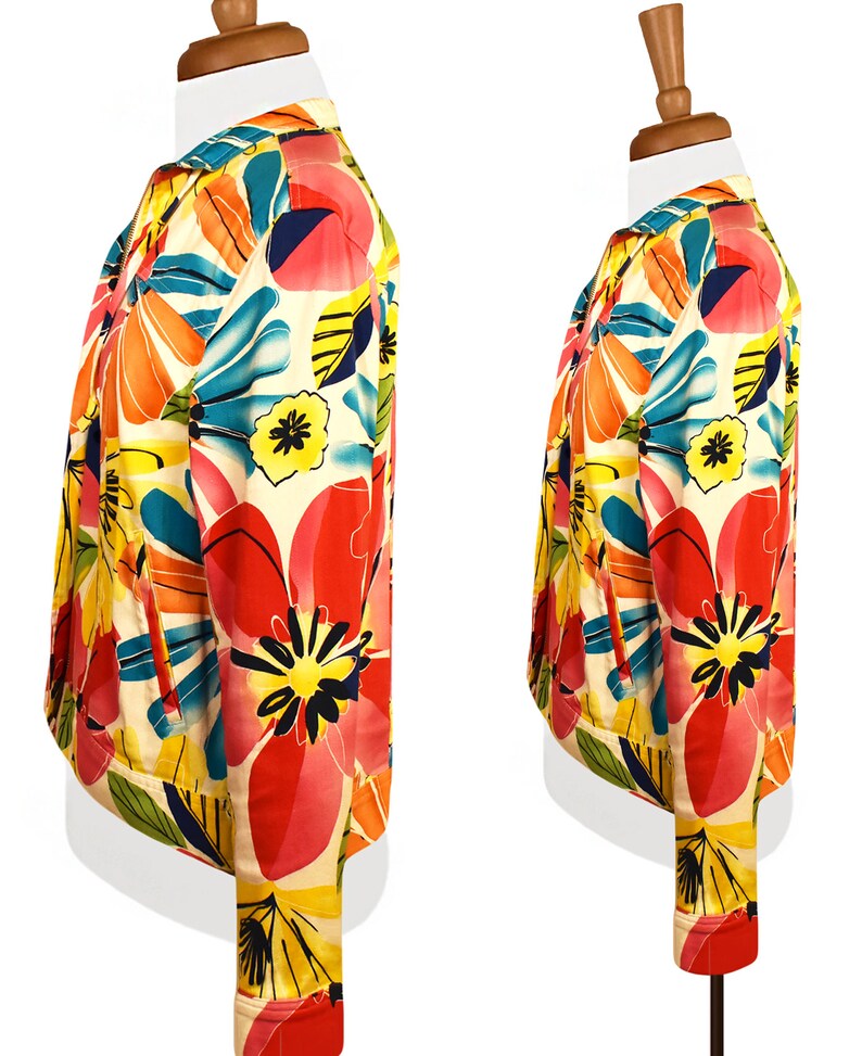 May include: A white jacket with a colorful floral print. The print features large pink, orange, yellow, and blue flowers on a white background.
