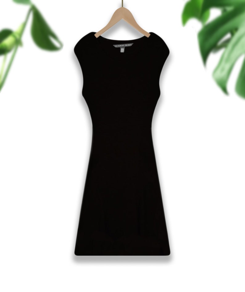 May include: A black sleeveless dress with a scoop neck and a fitted silhouette. The dress has a small tag that says "Victoria's Secret" on the front.