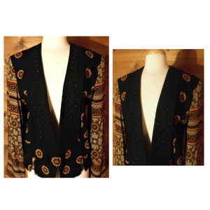 May include: A black blazer with a gold and brown patterned design on the sleeves. The blazer has a deep V-neck and a fitted silhouette.