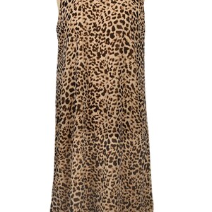 May include: A sleeveless dress with a leopard print pattern in shades of brown and beige. The dress has a loose, flowing silhouette and a round neckline.
