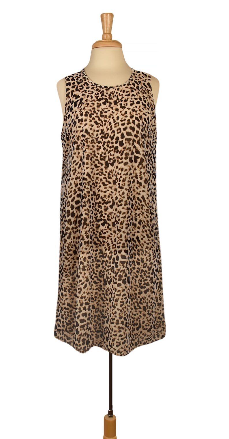 May include: A sleeveless dress with a leopard print pattern in shades of brown and beige. The dress has a loose, flowing silhouette and a round neckline.