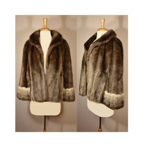 Peut inclure: Une veste en fausse fourrure marron avec un col ch&acirc;le et des manches longues. Les poignets sont bord&eacute;s d'une fourrure marron plus claire.