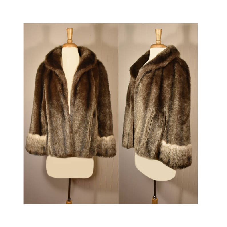 Peut inclure: Une veste en fausse fourrure marron avec un col ch&acirc;le et des manches longues. Les poignets sont bord&eacute;s d'une fourrure marron plus claire.