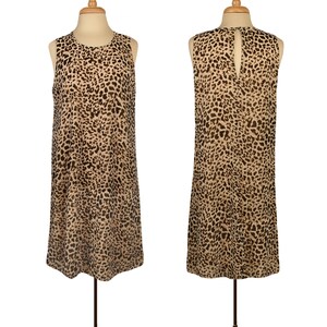 May include: A sleeveless, knee-length dress with a leopard print pattern. The dress has a round neckline and a keyhole opening in the back.