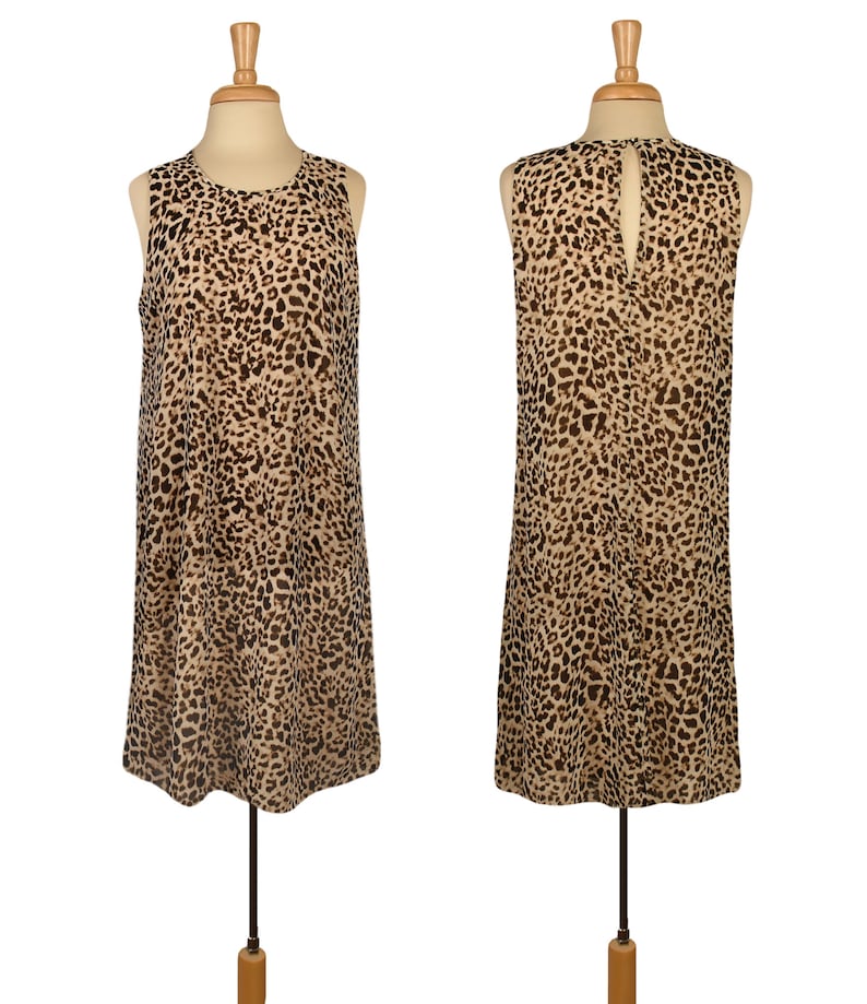 May include: A sleeveless, knee-length dress with a leopard print pattern. The dress has a round neckline and a keyhole opening in the back.