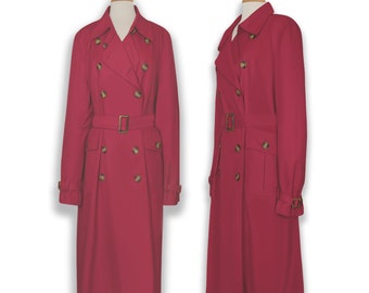 Puede incluir: Una gabardina larga de doble botonadura de color rojo intenso. La gabardina tiene cinturón, bolsillos de solapa y botones dorados.