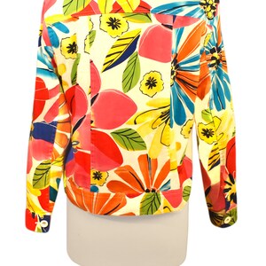 May include: A white denim jacket with a colorful floral print. The print features large flowers in shades of pink, red, yellow, blue, and green.