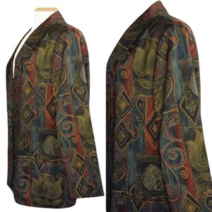 May include: A patterned blazer in shades of green, brown, and red, featuring geometric and floral designs. The blazer has a collarless design and two front pockets. The fabric has a textured appearance.