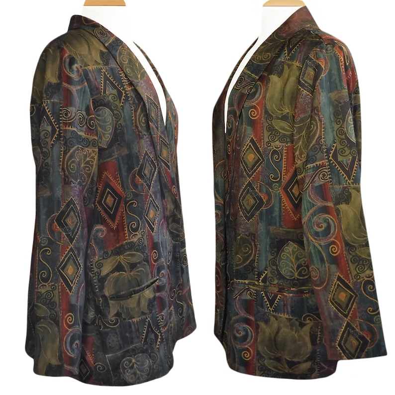 May include: A patterned blazer in shades of green, brown, red, and blue, displayed on a mannequin. The blazer features a geometric and floral design, with a notched collar and two front pockets. The fabric has a textured appearance.
