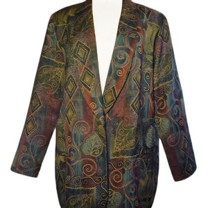 May include: A patterned blazer in shades of green, brown, and blue. The blazer features a unique design with diamond and swirl patterns. It has a classic lapel and two front pockets. The blazer is displayed on a white mannequin.