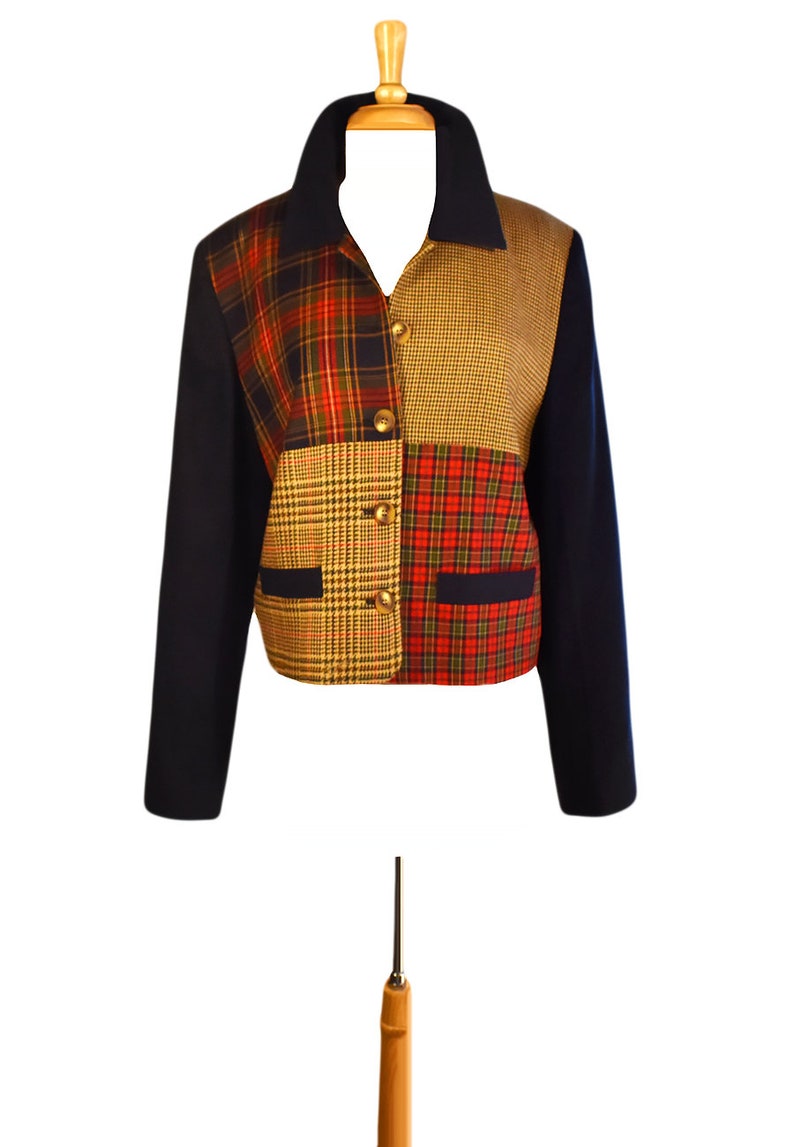 May include: A navy blue blazer with a patchwork design featuring red, yellow, and brown plaid patterns. The blazer has a collar and long sleeves.