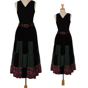 Könnte beinhalten: Ein schwarzes, ärmelloses Kleid mit einem grün-schwarzen Patchwork-Rock. Der Rock hat einen bunten, gemusterten Saum. Das Kleid ist mit einem braunen Ledergürtel gegürtet.
