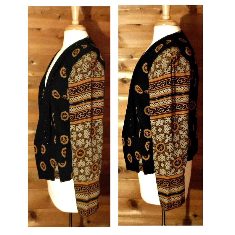 May include: A black and gold patterned jacket with a V-neck and long sleeves. The jacket has a geometric pattern with a black background and gold accents.