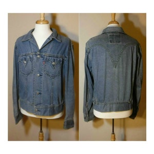 May include: A light blue denim jacket with a button closure, two chest pockets, and two front pockets. The jacket has a pointed collar and long sleeves.