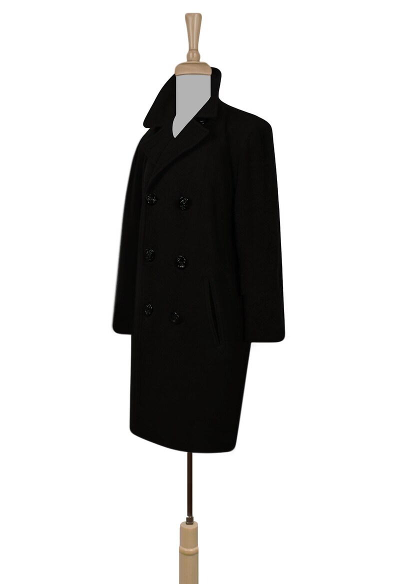 K&ouml;nnte beinhalten: Ein schwarzer Peacoat mit doppelreihigem Verschluss und vier schwarzen Kn&ouml;pfen. Der Mantel hat zwei Pattentaschen auf der Vorderseite.