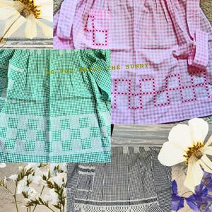May include: A collage of vintage aprons in pink, green, and black and white gingham patterns. Each apron features decorative cross-stitch details and pockets. One apron has the text "SO YOU ENJOY THE SUNNY".