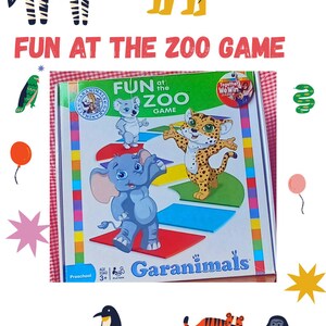 Può includere: Un colorato gioco da tavolo intitolato "FUN AT THE ZOO GAME" con animali dei cartoni animati come una zebra, un leone e un elefante. Il gioco è progettato per bambini dai 3 anni in su, con il marchio "Garanimals".
