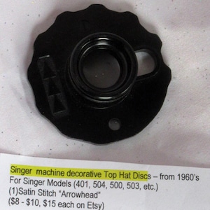 May include: Black Singer machine decorative Top Hat Disc. The disc has a circular design with a central opening and a side loop. The text on the image says "Singer machine decorative Top Hat Discs - from 1960's".