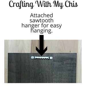 May include: Dark brown wooden panel with an attached sawtooth hanger for easy hanging. The text "Crafting With My Chis" is at the top. Below the text is the text "Attached sawtooth hanger for easy hanging."