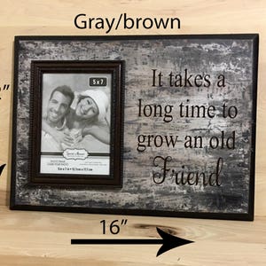 May include: A gray and brown wooden picture frame, 16 inches wide and 12 inches tall, with a 5x7 inch photo. The frame has the text "It takes a long time to grow an old Friend."