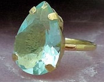 Op de afbeelding: Een gouden ring met een grote, traanvormige lichtblauwe edelsteen.