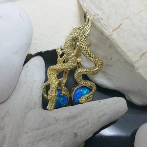 May include: Gold dragon earrings with blue opal stones. The dragon is curled around the stones, creating a unique and eye-catching design.