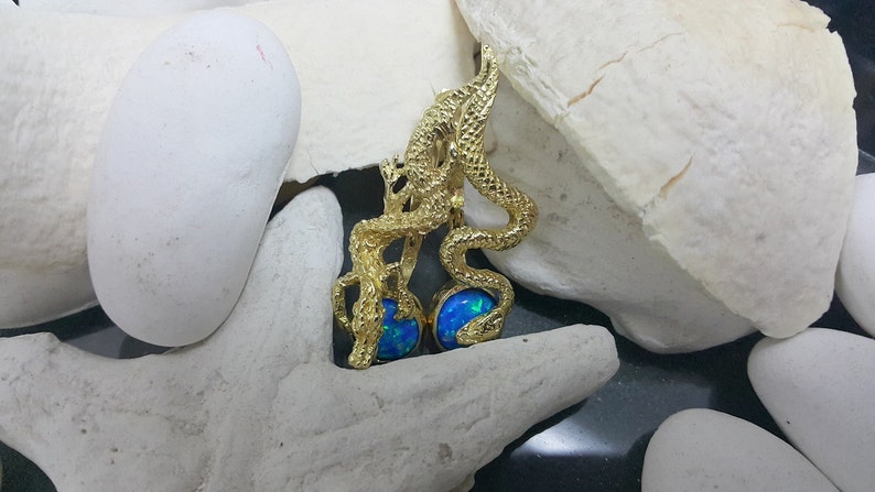 May include: Gold dragon earrings with blue opal stones. The dragon is curled around the stones, creating a unique and eye-catching design.
