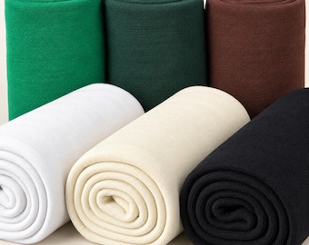 May include: Six rolls of fabric arranged in two rows. The top row features bright green, dark forest green, and chocolate brown rolls. The bottom row consists of white, cream, and black rolls. Each roll displays a consistent, fine-knit texture.