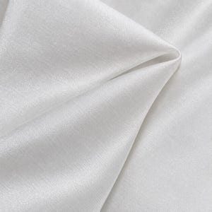 May include: A solid white fabric with a subtle, fine-grained texture and a soft, reflective sheen. The material is draped in gentle folds, highlighting the smooth surface and the consistent, bright white color throughout the entire textile.