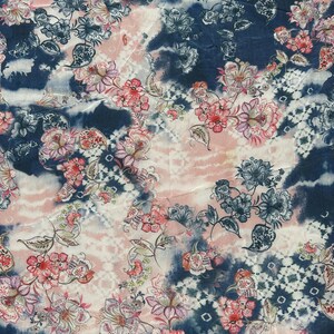Puede incluir: Tela con estampado floral en tonos rosa, blanco y azul marino. El diseño presenta varias flores y hojas, con un efecto tie-dye en el fondo. La tela tiene una apariencia suave y fluida.