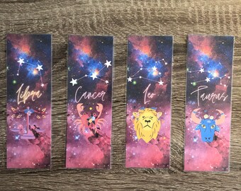 May include: Four colorful bookmarks with a galaxy background and zodiac signs. The signs are Libra, Cancer, Leo, and Taurus. Each bookmark features a constellation, a symbol, and the name of the sign.