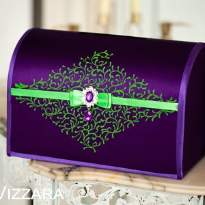 May include: A purple satin wedding card box with a green and white floral design and a purple jewel accent.