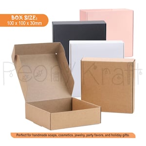 Op de afbeelding: Een collectie vierkante kartonnen verzenddozen in bruin, zwart, wit en lichtroze. Eén bruine doos is geopend en toont de binnenkant. De tekst "BOX SIZE: 100 x 100 x 30mm" is zichtbaar in de linkerbovenhoek van de afbeelding.