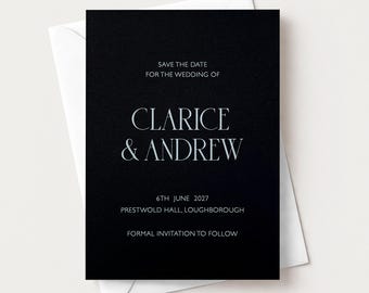 May include: A black rectangular save the date card with white text that reads: SAVE THE DATE FOR THE WEDDING OF CLARICE & ANDREW 6TH JUNE 2027 PRESTWOLD HALL, LOUGHBOROUGH FORMAL INVITATION TO FOLLOW. The card is placed on top of a white envelope.