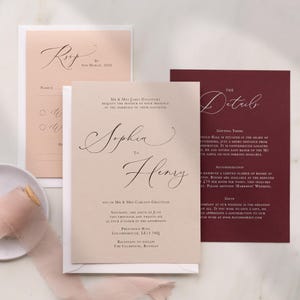 Op de afbeelding: Elegante trouwuitnodigingsset met drie kaarten in blush, crème en bordeaux. De centrale kaart kondigt "Sophia to Henry" aan in sierlijke letters. De RSVP-kaart is gedateerd 9 maart 2026. De detailkaart bevat accommodatie- en cadeau-informatie.
