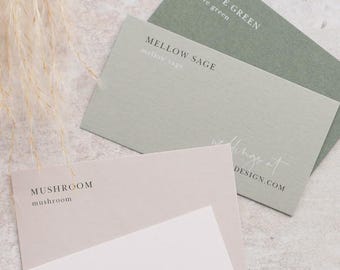 May include: A stack of rectangular paper cards in shades of olive green, sage green, mushroom, and white. The cards feature printed text including the words OLIVE GREEN, MELLOW SAGE, MUSHROOM, and CALICO, along with website text and small graphic symbols.