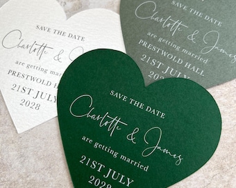 May include: Heart-shaped wedding save-the-date cards in ivory, green, and dark green. Each card features the text "Save the Date," the names "Charlotte & James," and the wedding date, "21st July 2028," in elegant white script.