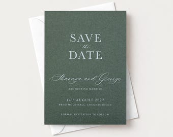 May include: A dark green rectangular save the date card with white text reading SAVE the DATE, Shanaya and George ARE GETTING MARRIED, 14TH AUGUST 2027, PRESTWOLD HALL, LOUGHBOROUGH, FORMAL INVITATION TO FOLLOW, resting on a white envelope.