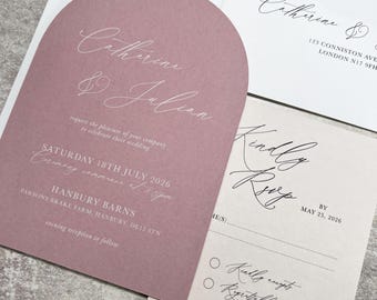 May include: An arched dusty rose wedding invitation with white text reading Catherine & Julian, Saturday 18th July 2026, Hanbury Barns, and a matching RSVP card with black text reading Kindly RSVP by May 25, 2026, and a white envelope.