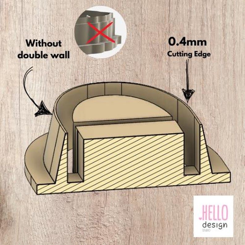 Puede incluir: Un cortador de galletas de madera con un borde de corte de 0,4 mm. El cortador tiene la forma de un semic&iacute;rculo con un rect&aacute;ngulo m&aacute;s peque&ntilde;o en el centro. El texto "0,4 mm Cutting Edge" est&aacute; impreso en la imagen.