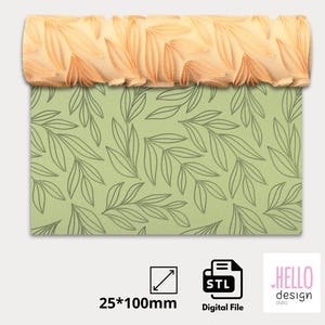 Puede incluir: Un rodillo de madera con un diseño de patrón de hojas. El rodillo tiene 25 mm de ancho y 100 mm de largo. El rodillo se muestra sobre un fondo verde con un patrón de hojas.