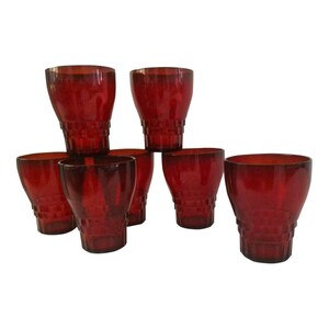 May include: Set of six red glass tumblers with a textured design. The glasses are stacked in a pyramid shape.
