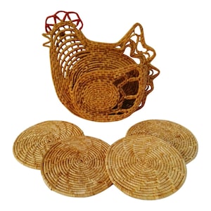 May include: A woven wicker chicken-shaped basket with a red and white trim. The basket is surrounded by four round woven wicker coasters.
