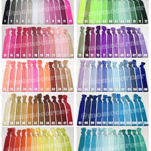 Könnte beinhalten: Ein Set mit 120 bunten Haargummis, angeordnet in Reihen zu 12. Die Haargummis bestehen aus einem dehnbaren, elastischen Material und sind in verschiedenen Farben erhältlich, darunter Rot, Blau, Grün, Gelb, Pink, Lila, Orange, Braun und Schwarz.