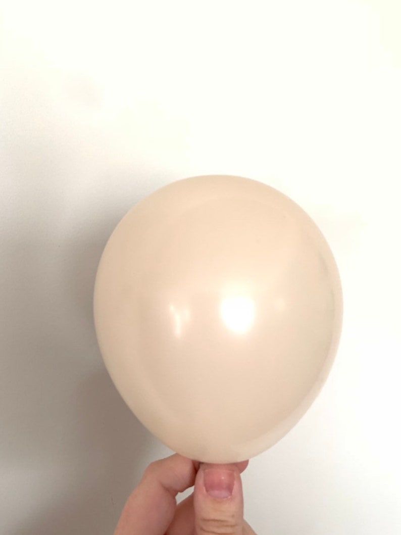 May include: A single, off-white balloon, inflated and held by a hand.