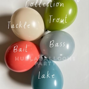 May include: A set of five balloons with fishing-themed text. The balloons are in the colors green, beige, gray, red, and blue. The text on the balloons reads "Trout", "Tackle", "Bass", "Bait", and "Lake".